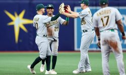 ST. PETERSBURG, FL - APRIL 13: Chad Pinder #10 of the Oakland Athletics, left, celebrates with Cristian Pache #20 and Stephen Piscotty #25 after a win over the Tampa Bay Rays in a baseball game at Tropicana Field on April 13, 2022 in St. Petersburg, Florida. (Photo by Mike Carlson/Getty Images)